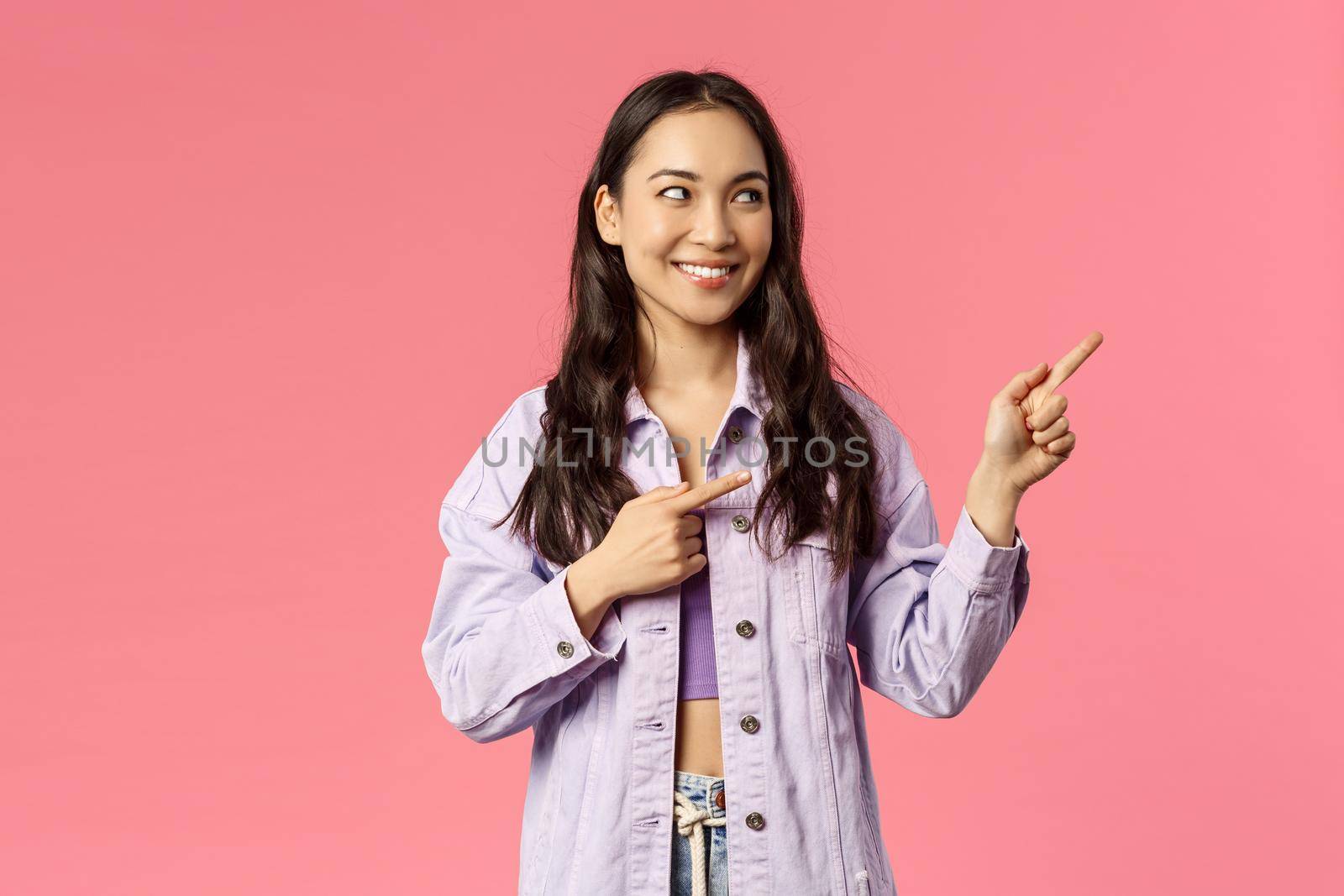 Portrait of curious good-looking asian girl seeing something interesting, peeking and pointing fingers right at promo, look at online courses advertisement, cafe or product promotion by Benzoix