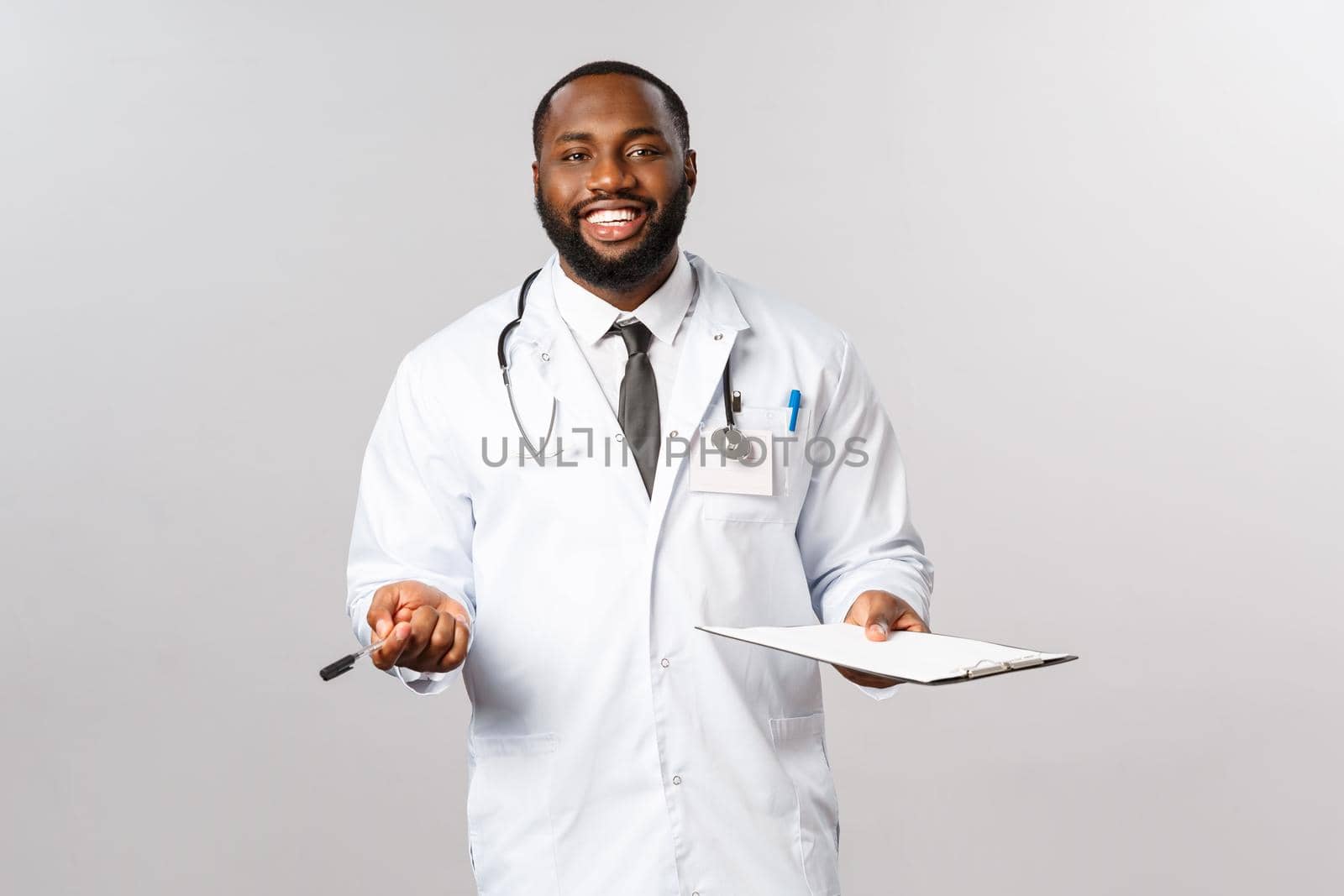 Medicine, covid19, treatment and hospital concept. Happy friendly african-american doctor, physician treating patient, have check-up in ambulance or hospital, smiling hold clipboard.