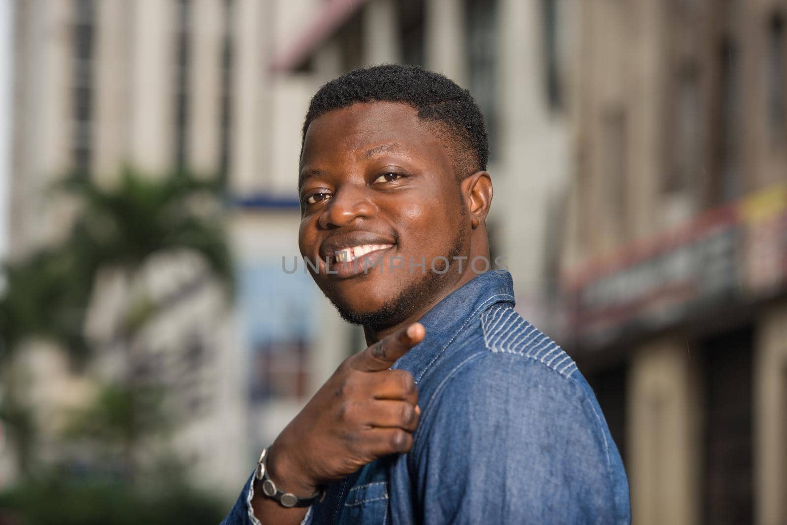 young african man standing in jeans looking at camera smiling.