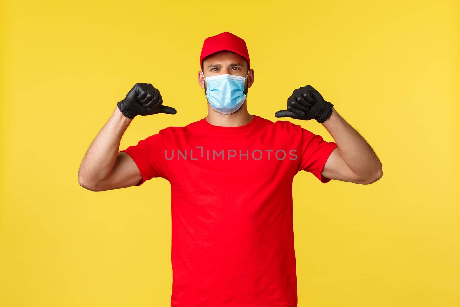 Express delivery during pandemic, covid-19, safe shipping, online shopping concept. Confident and determined courier in red uniform, medical mask, pointing himself serious, hero deliver order.