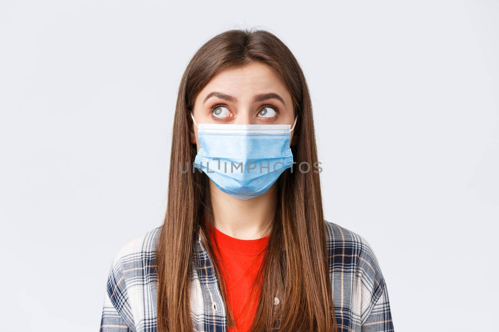 Coronavirus outbreak, leisure on quarantine, social distancing and emotions concept. Close-up of thoughtful, young woman in medical mask, look upper left corner reading sign or have bubble thought by Benzoix