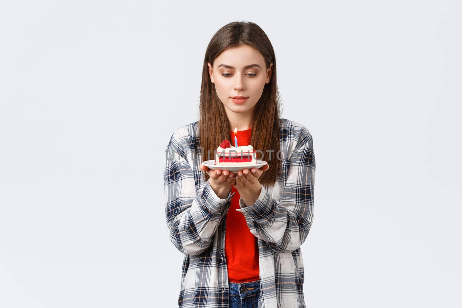 People lifestyle, holidays and celebration, emotions concept. Dreamy attractive birthday girl, woman celebrating b-day, making wish look at lit candle on cake, white background by Benzoix