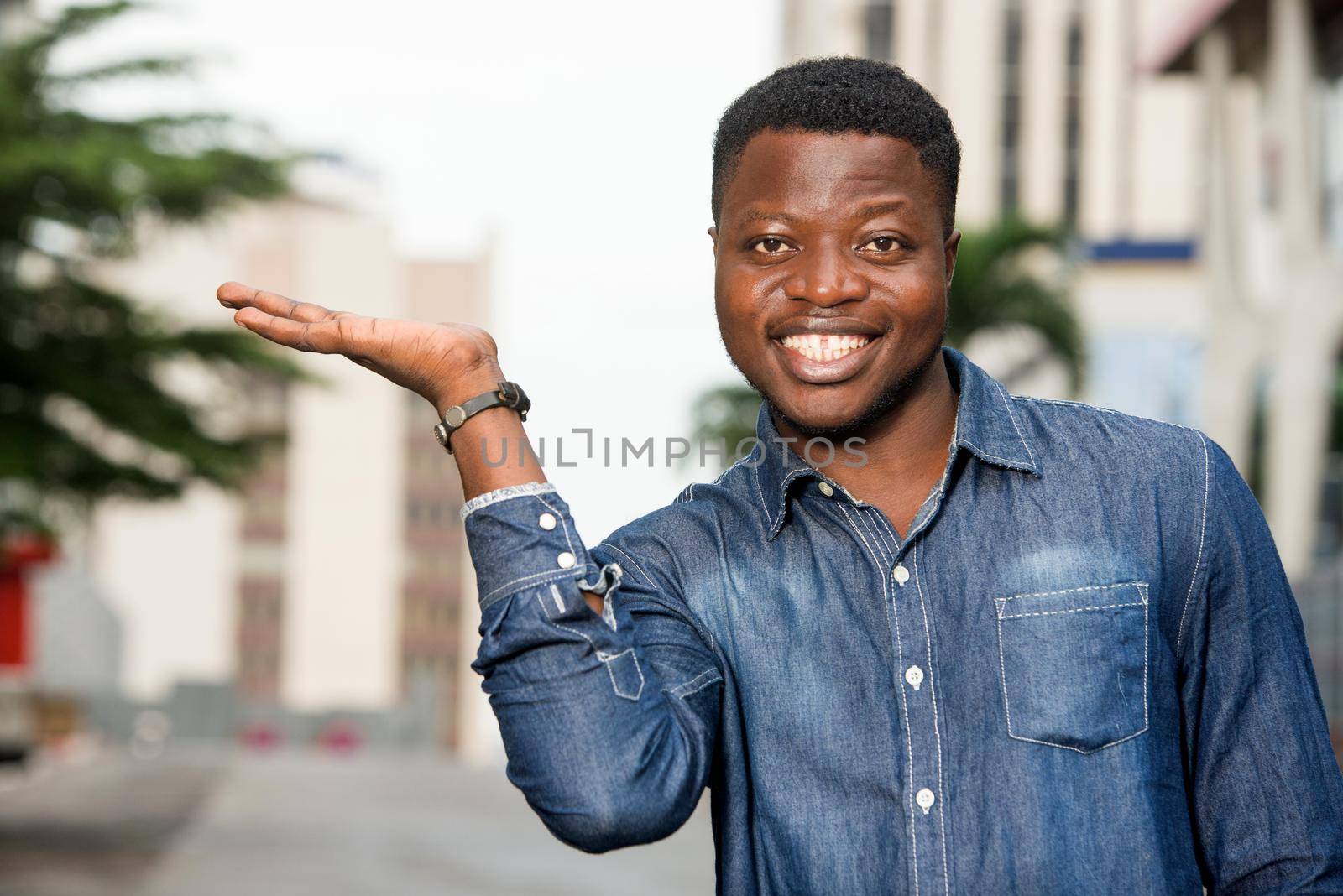 portrait of young happy man in shirt gesturing a welcome sign showing something of the hand