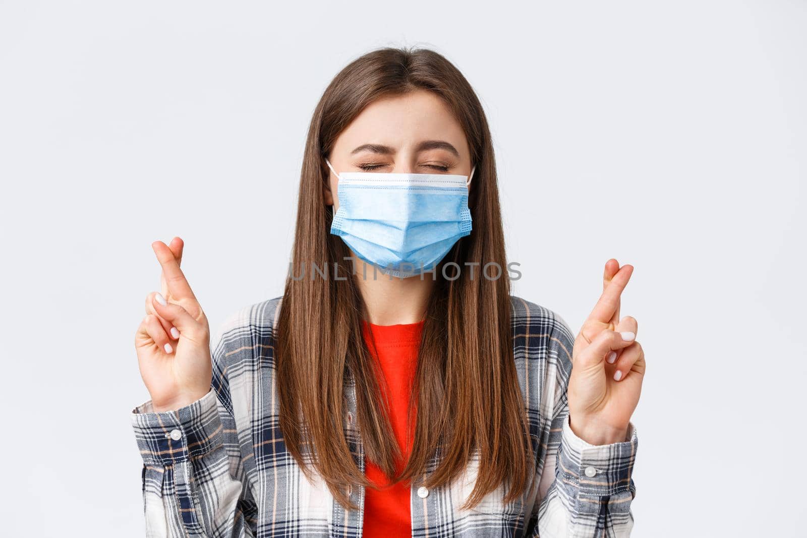 Coronavirus outbreak, leisure on quarantine, social distancing and emotions concept. Close-up of hopeful, dreamy young girl making wish, close eyes and cross fingers good luck.