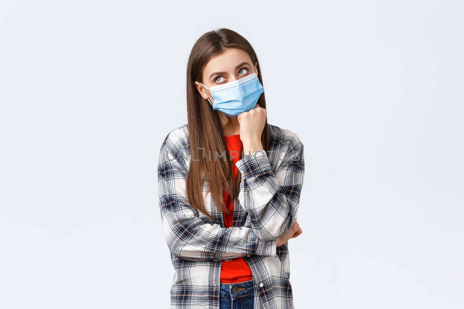 Coronavirus outbreak, leisure on quarantine, social distancing and emotions concept. Thoughtful and gloomy young woman hate staying home self-isolation, dreaming go vacation, wear medical mask.