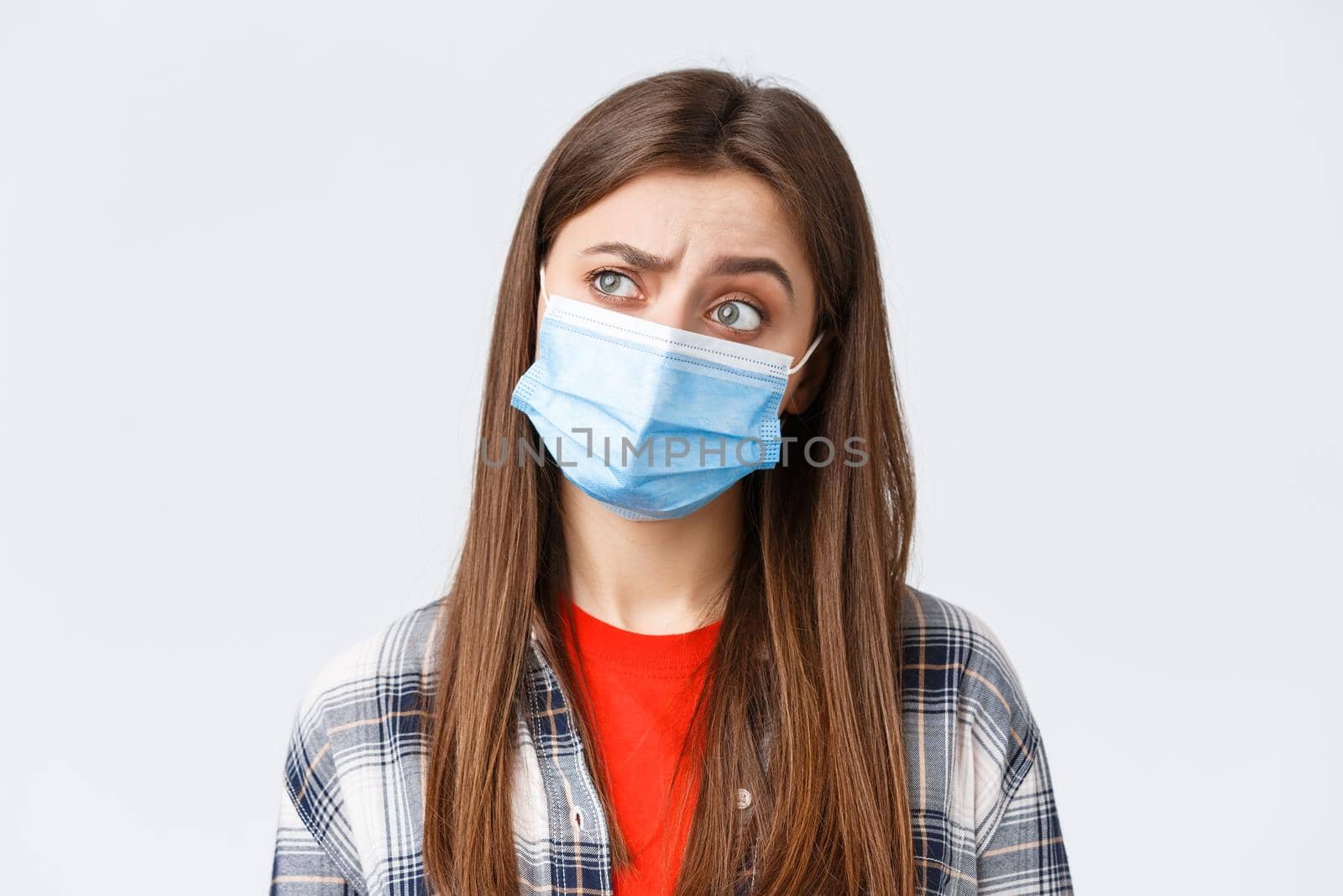 Coronavirus outbreak, leisure on quarantine, social distancing and emotions concept. Thoughtful and intrigued woman in medical mask, looking left with interest, thinking, white background by Benzoix