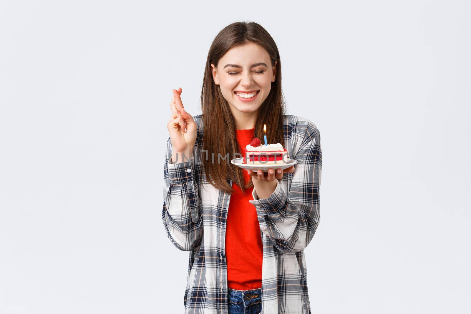People lifestyle, holidays and celebration, emotions concept. Happy, cheerful b-day girl celebrating, close eyes cross fingers as blowing candle to make wish on birthday cake.