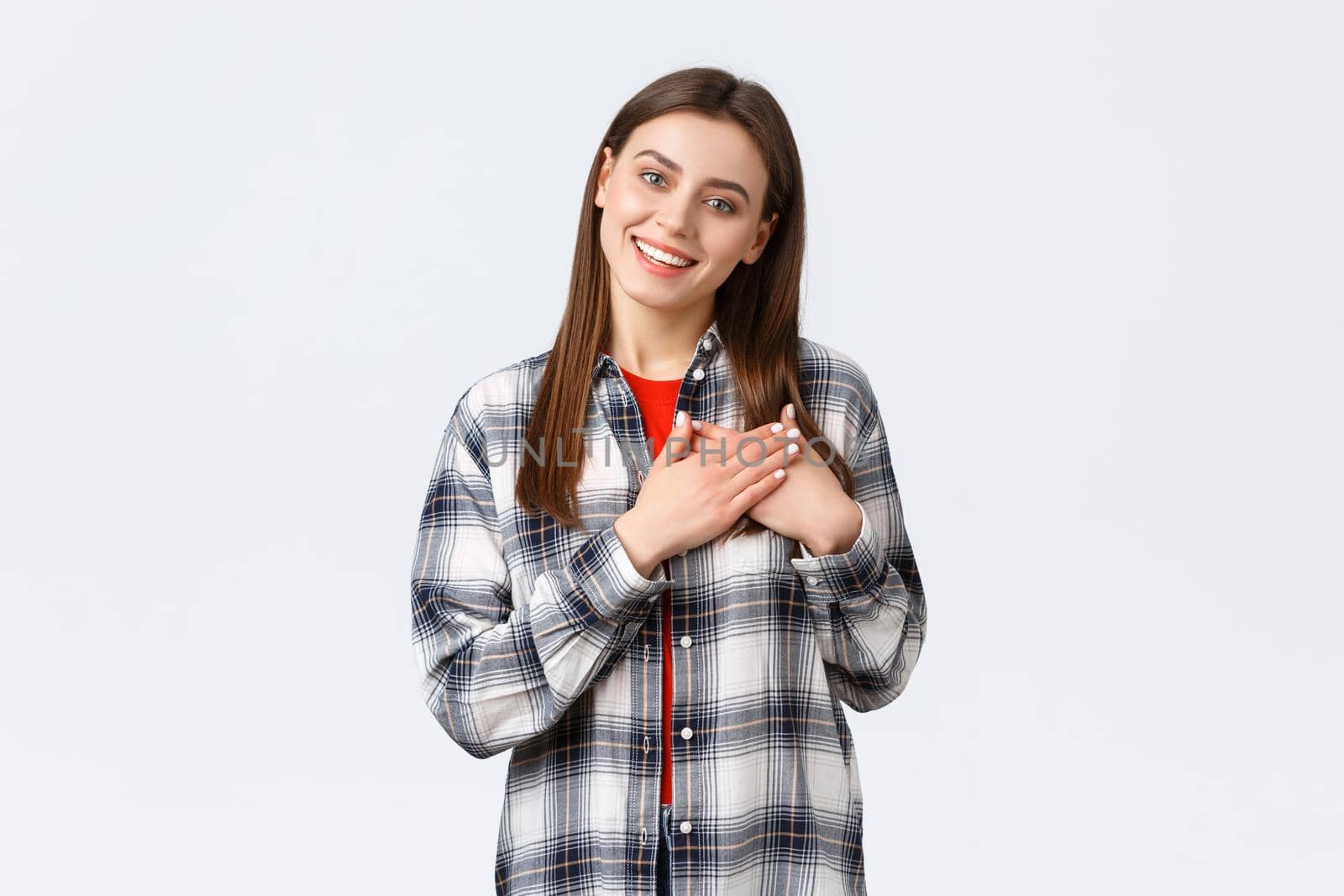 Lifestyle, different emotions, leisure activities concept. Touched tender young woman in checked shirt, hold hands on heart, being flattered, keep warm and tender memories in soul, smiling pleased by Benzoix