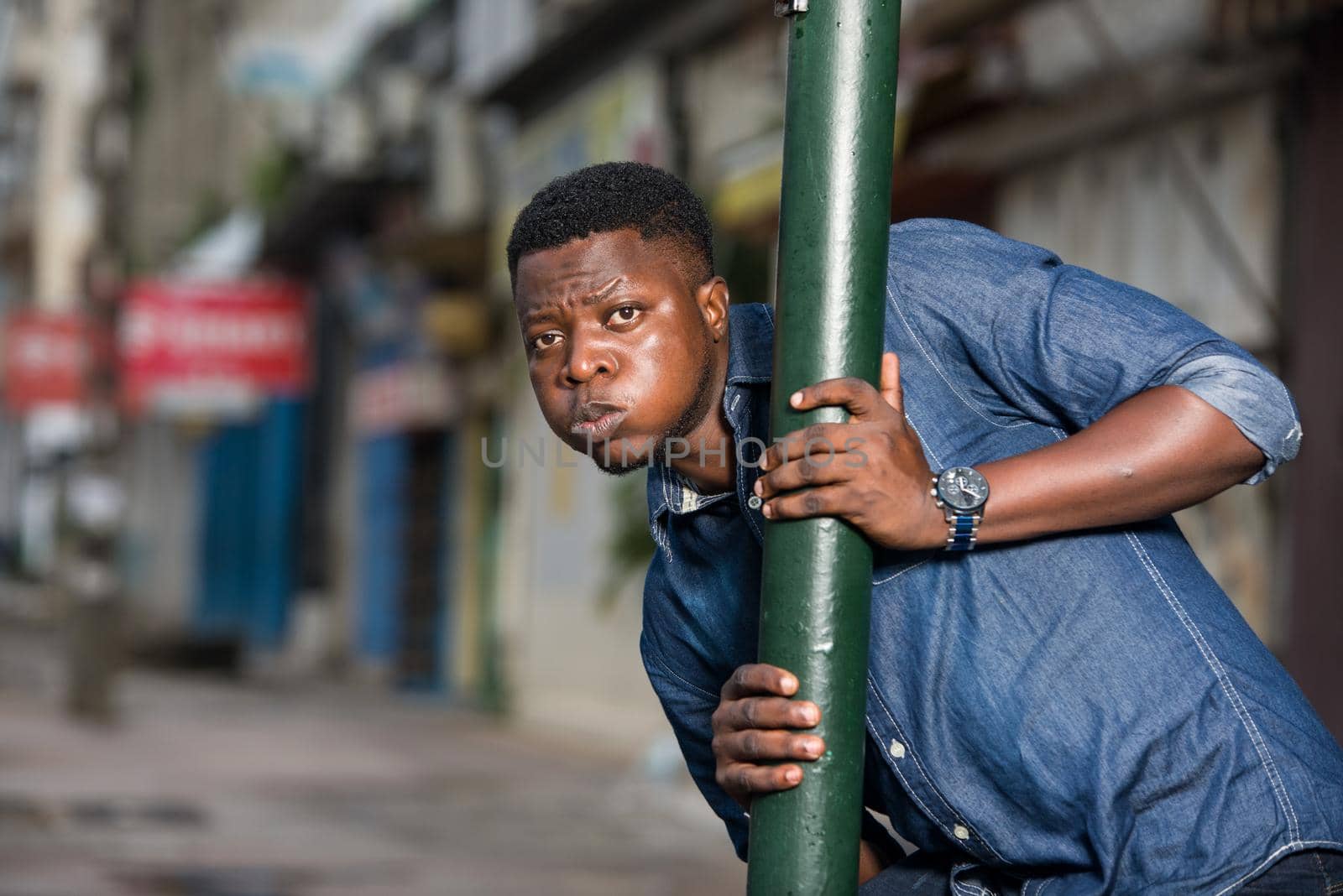 young african man behind iron bar looking at the camera, surprised.