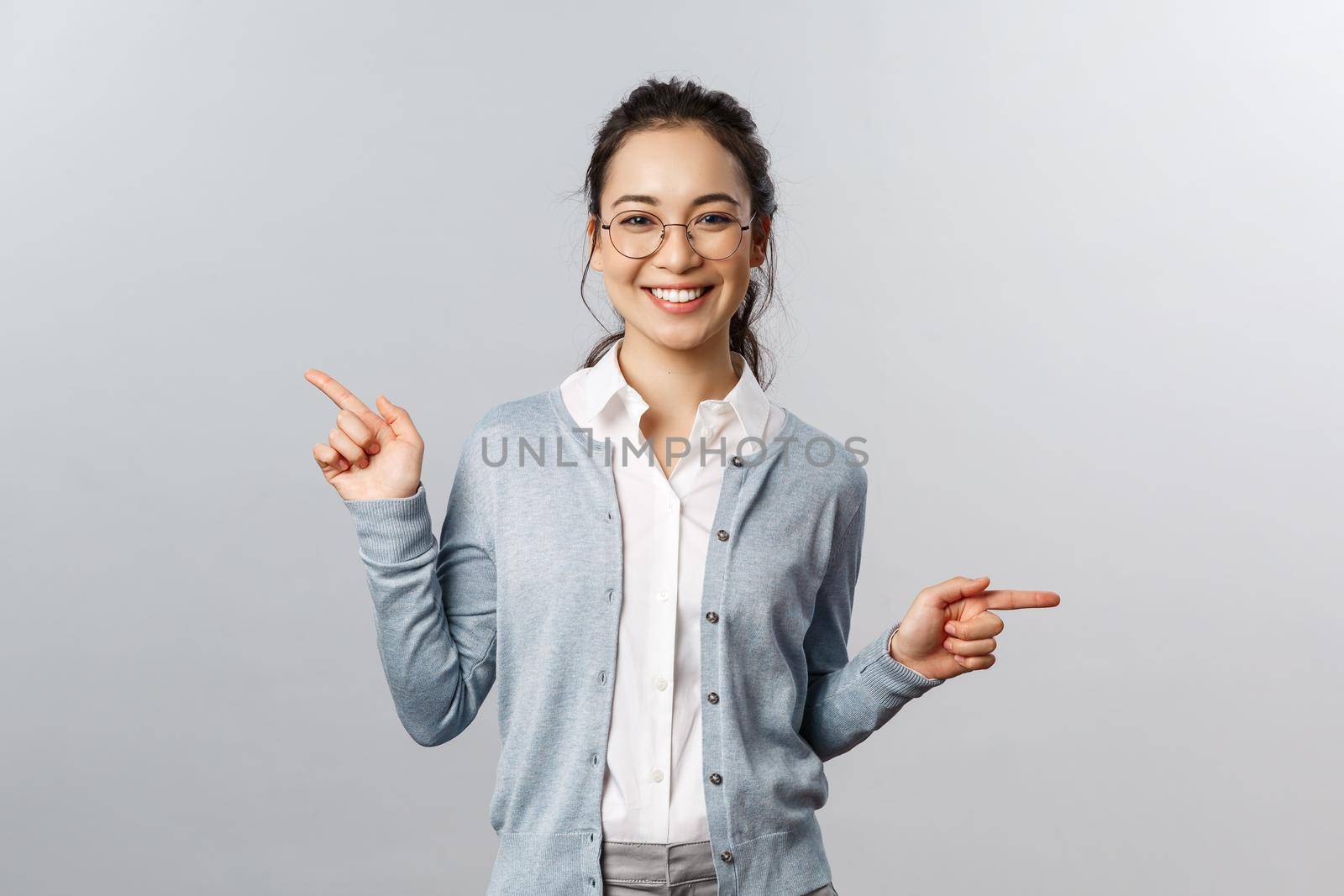 Advertisement, education and people concept. Girl recommends both products. Cheerful young asian woman in glasses pointing sideways, showing left and right promo with pleased smile.