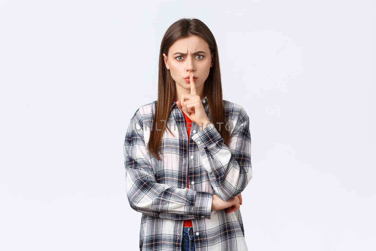 Lifestyle, different emotions, leisure activities concept. Angry serious-looking young woman tell shut up, keep quiet. Girl shushing at you with index finger pressed to lips, frowning disappointed.