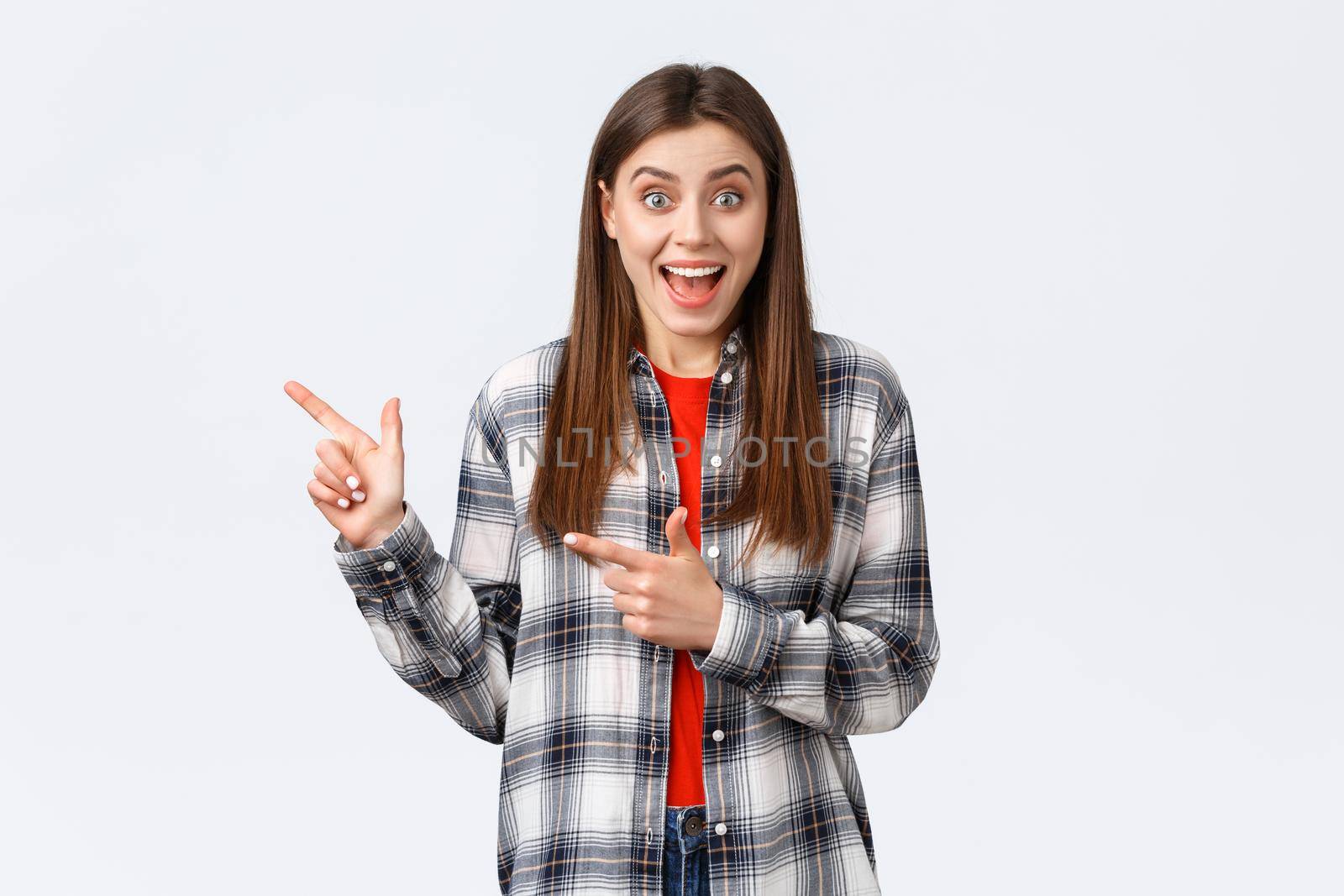 Lifestyle, different emotions, leisure activities concept. Excited female customer hear special discounts pointing shop promo. Astonished woman smiling happy and showing way, indicate left banner by Benzoix