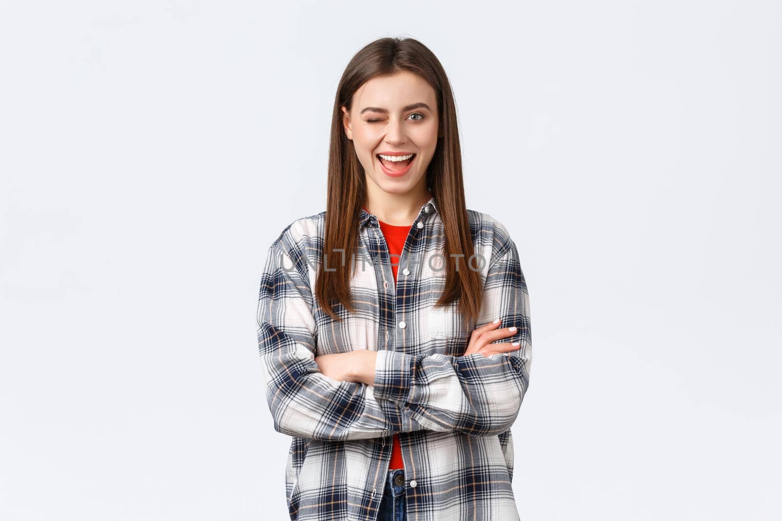 Lifestyle, different emotions, leisure activities concept. Enthusiastic and confident attractive woman, female student in checked casual shirt winking excited and smiling, cross arms chest ready.