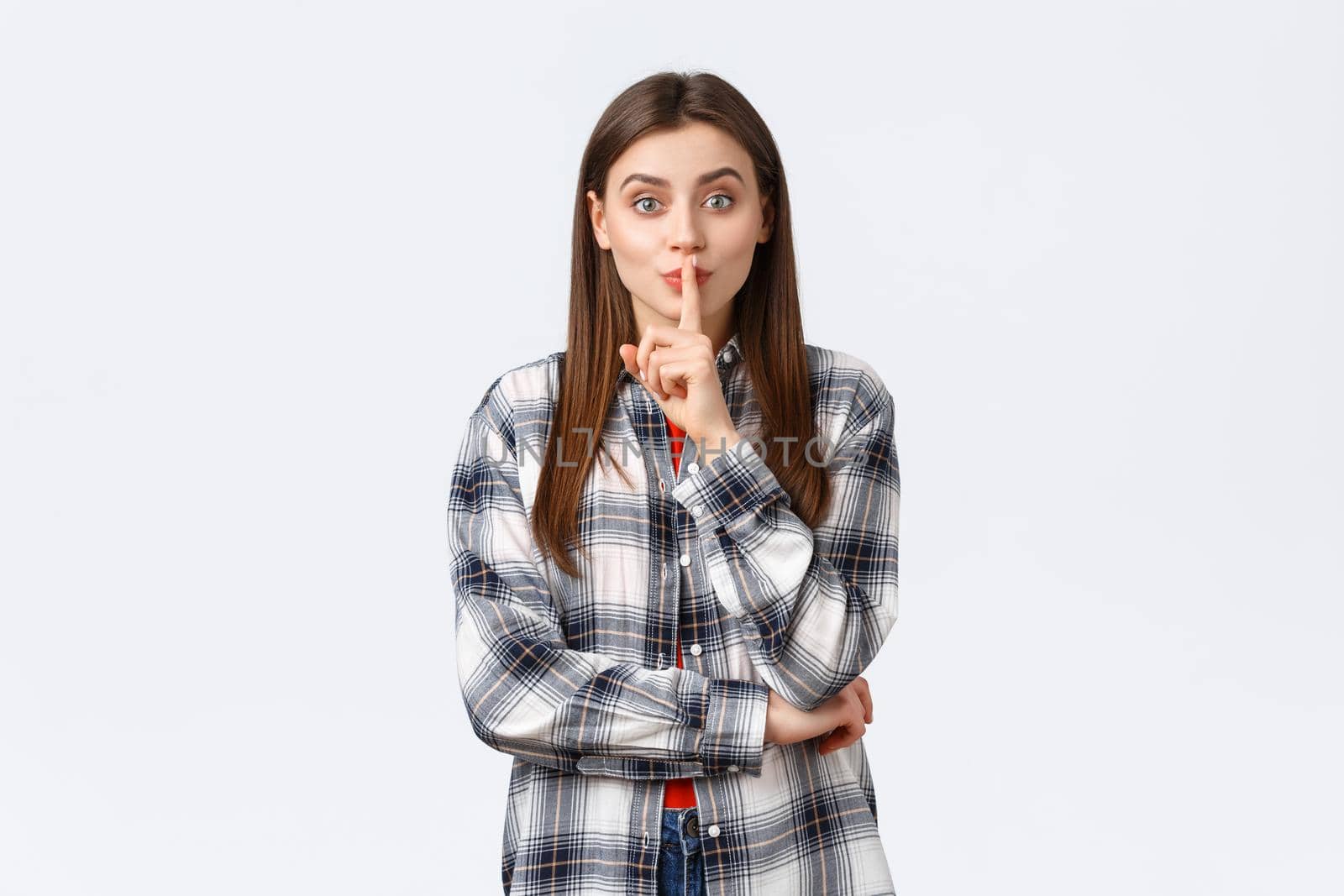 Lifestyle, different emotions, leisure activities concept. Silly cute girl in checked casual shirt asking keep secret, kindly shush with index finger over lips, want person keep voice down, be quiet by Benzoix