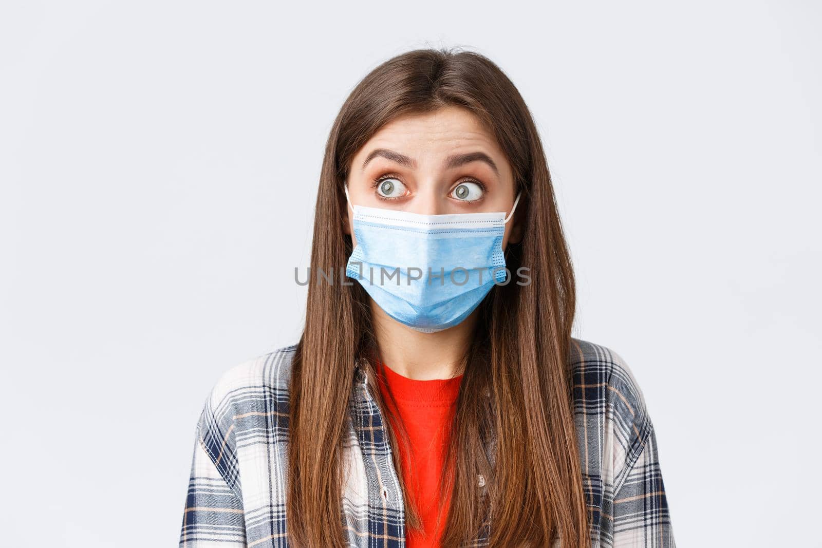 Coronavirus outbreak, leisure on quarantine, social distancing and emotions concept. Close-up of surprised caucasian woman in casual clothes and medical mask, staring left speechless by Benzoix