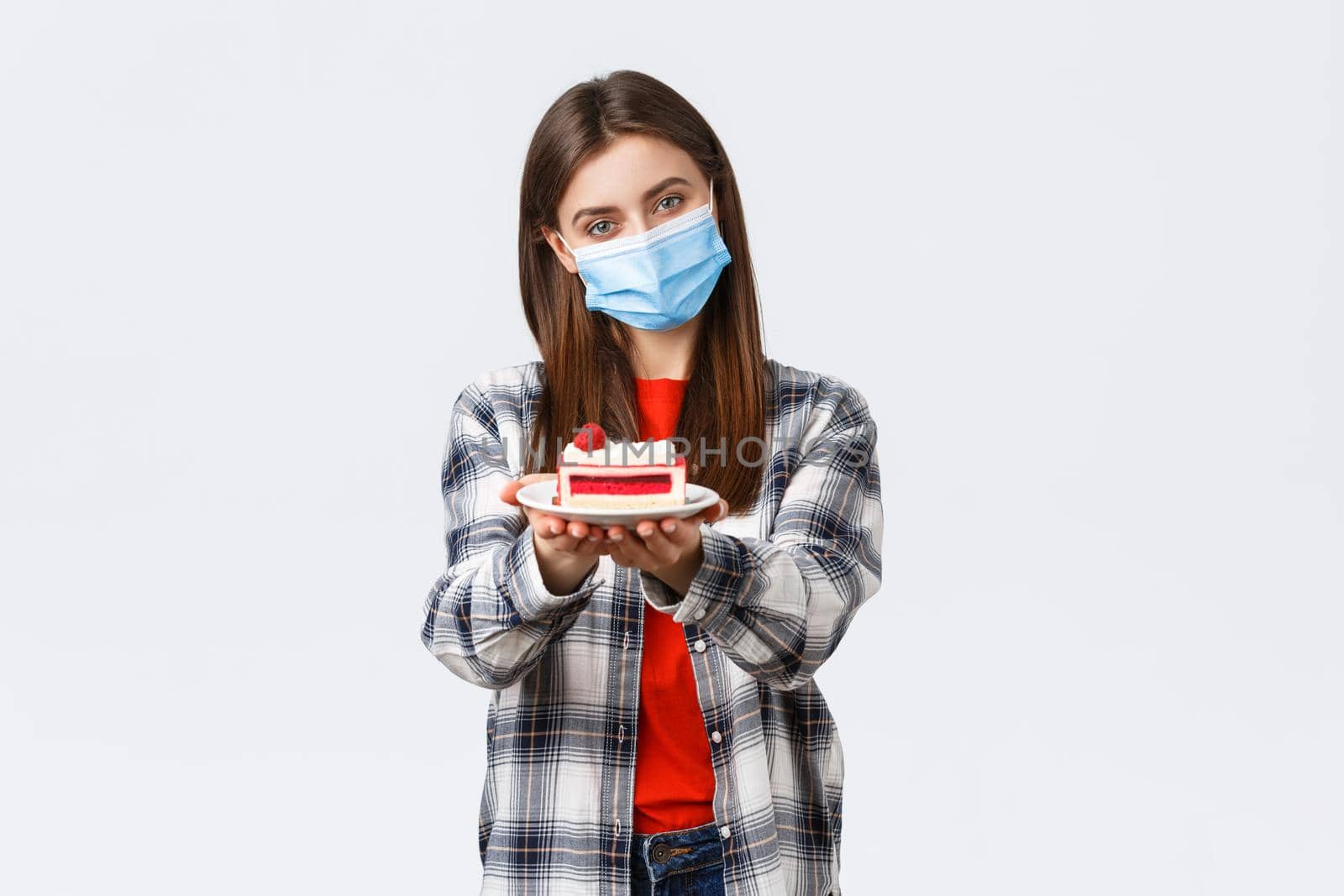 Coronavirus outbreak, lifestyle during social distancing and holidays celebration concept. Tender caring girlfriend made homemade cake, giving it to you, wear medical mask and smiling.