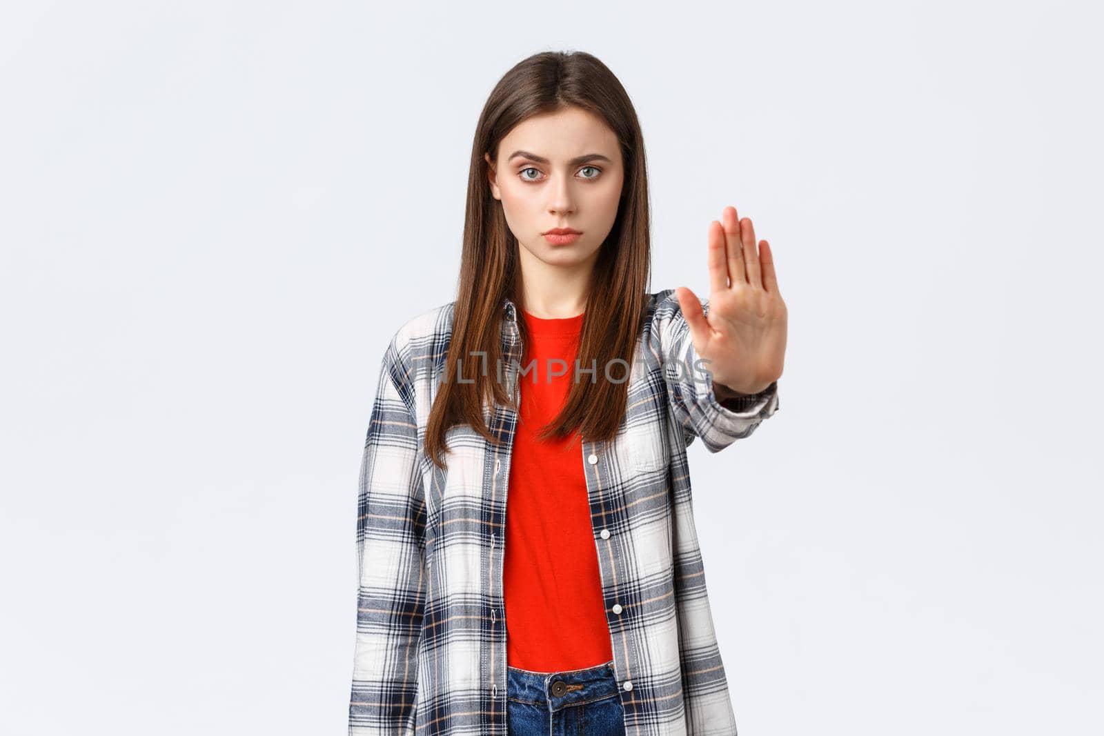 Lifestyle, different emotions, leisure activities concept. Time to stop. Serious young woman in casual outfit, stretch hand forward to prohibit, restrict or forbid something, white background.