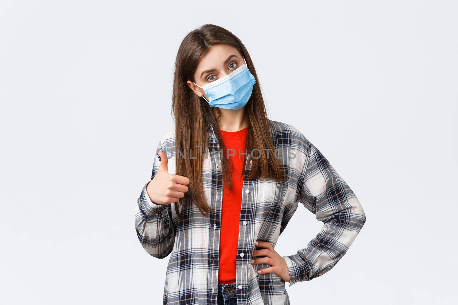 Coronavirus outbreak, leisure on quarantine, social distancing and emotions concept. Confident good-looking woman in medical mask give advice, recommend promo, show thumb-up in approval.