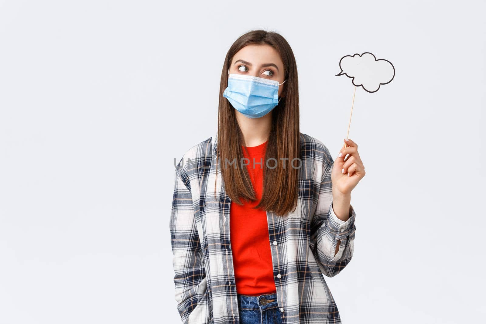 Coronavirus outbreak, leisure on quarantine, social distancing and emotions concept. Thoughtful smart young girl in medical mask searching for inspiration, thinking, holding commend cloud.