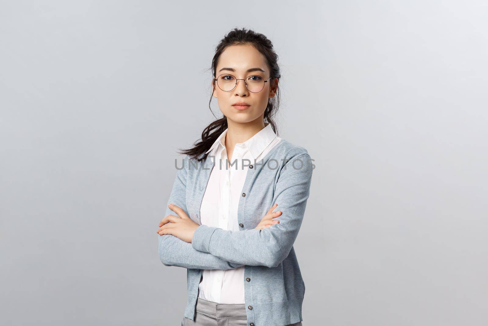 Serious-looking determined attractive asian woman, tutor or teacher starting online lesson with class standing self-assured with normal focused expression, cross arms on chest.