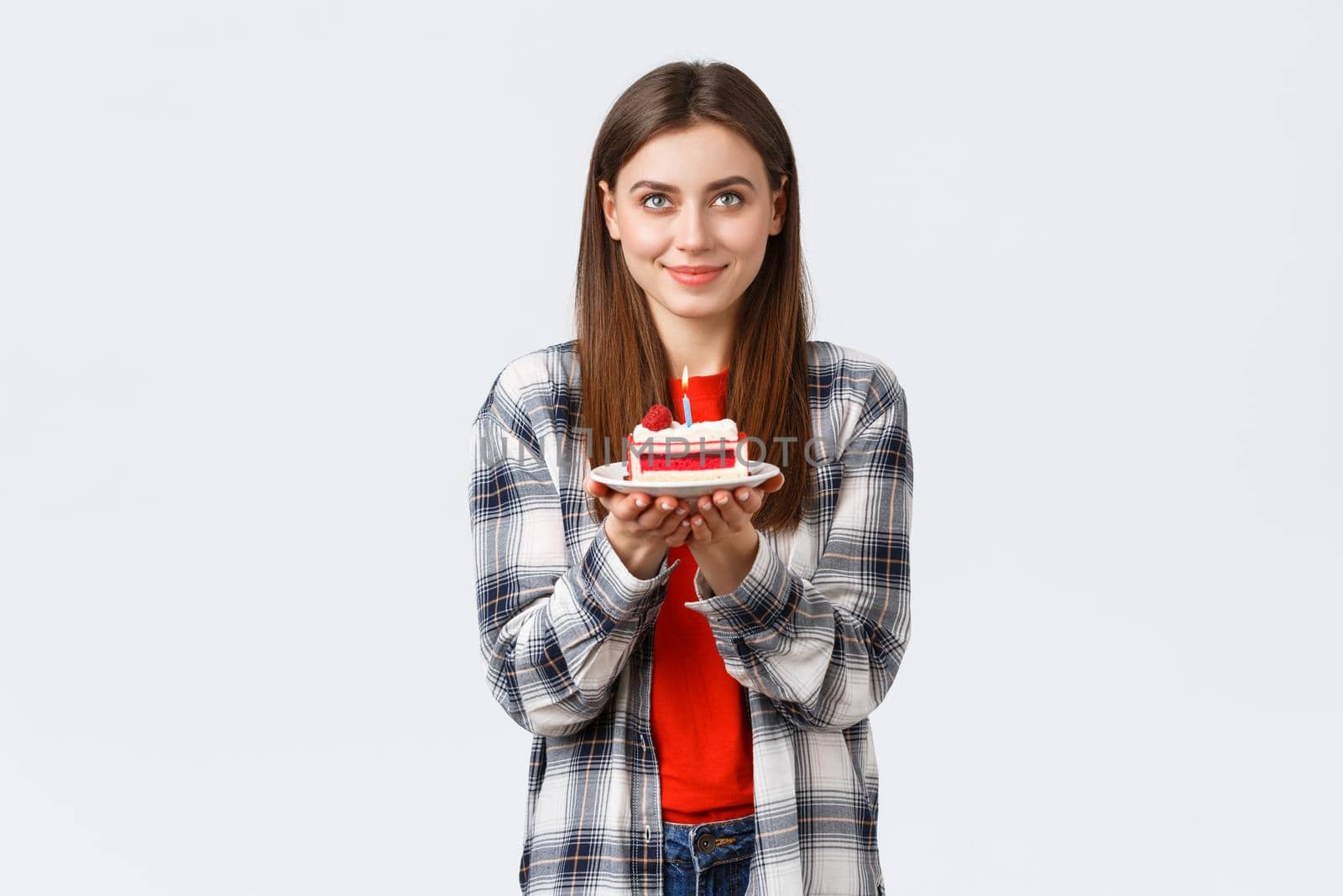 People lifestyle, holidays and celebration, emotions concept. Happy attractive girl looking up, imaging dream come true, making wish holding birthday cake with lit candle, white background by Benzoix
