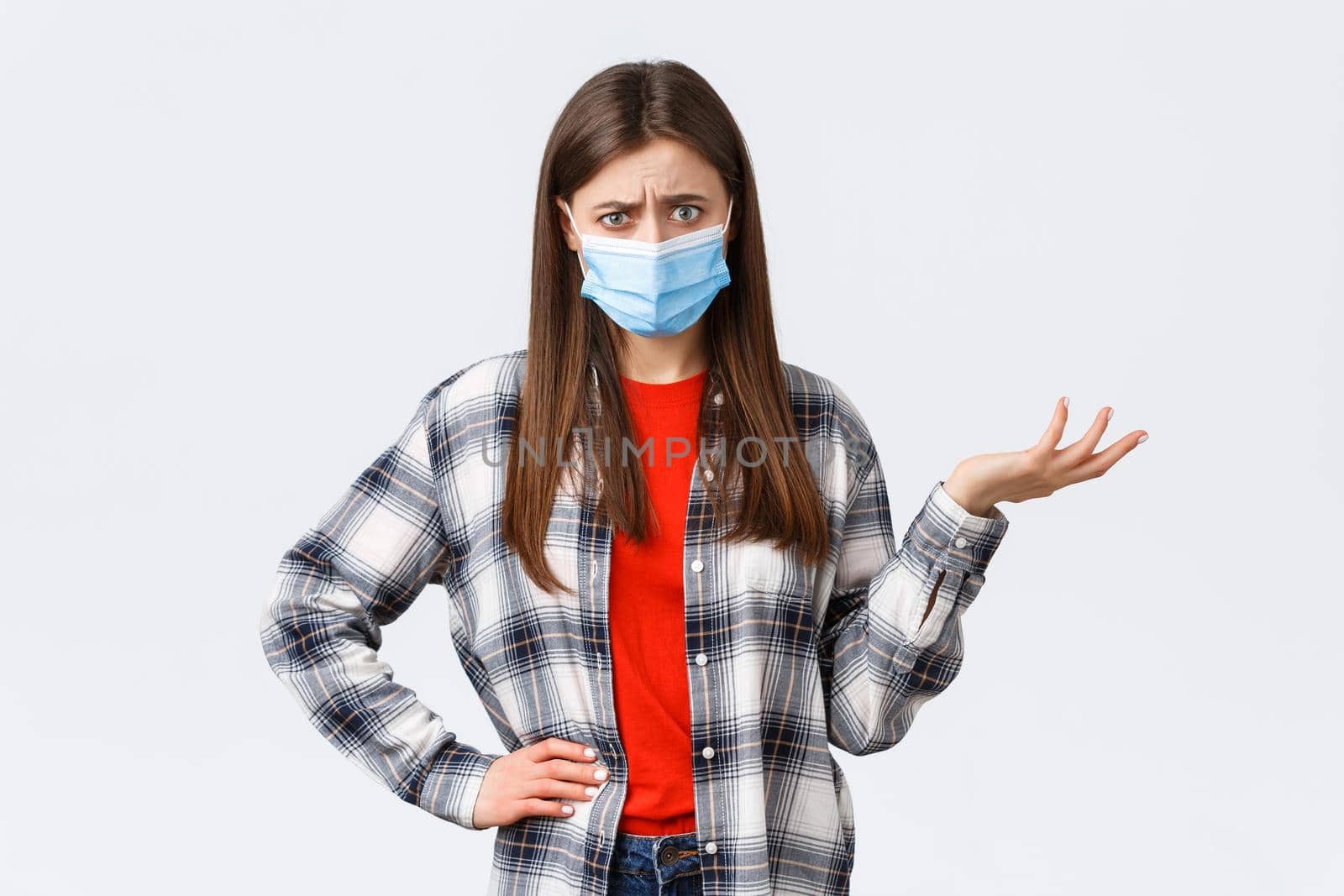 Coronavirus outbreak, leisure on quarantine, social distancing and emotions concept. Confused and bothered young woman cant understand this, shrug and stare puzzled camera, medical mask.