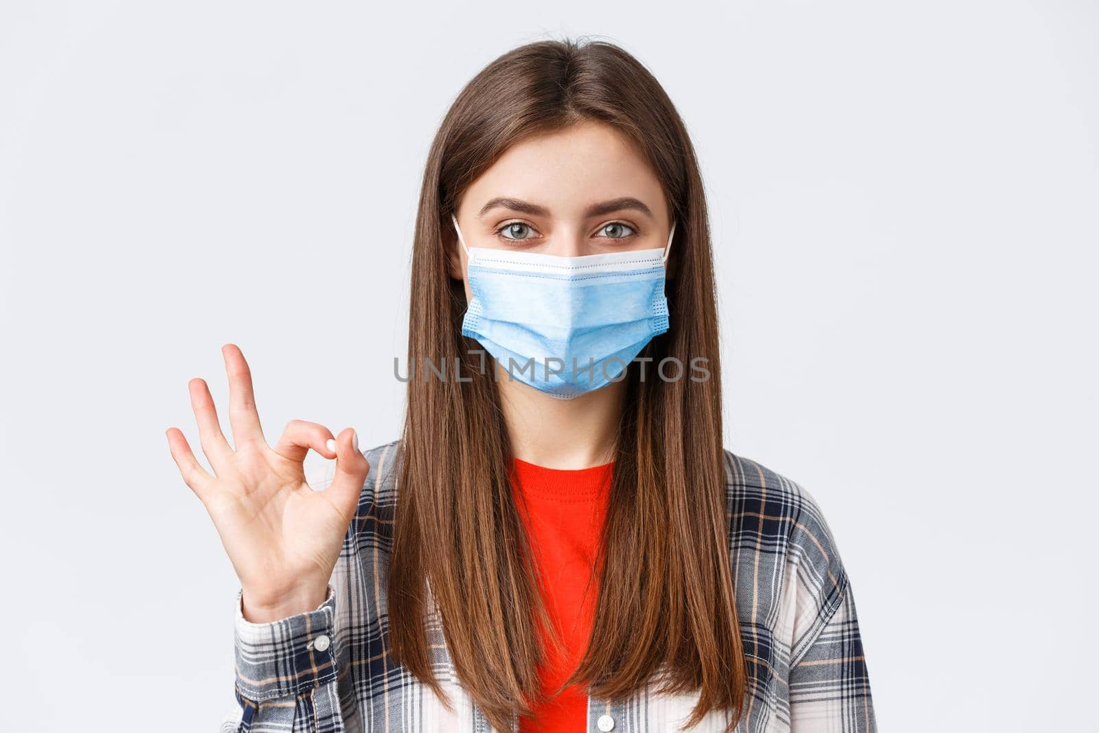 Coronavirus outbreak, leisure on quarantine, social distancing and emotions concept. Close-up of satisfied good-looking woman in medical mask, assure all good, show okay guarantee gesture.