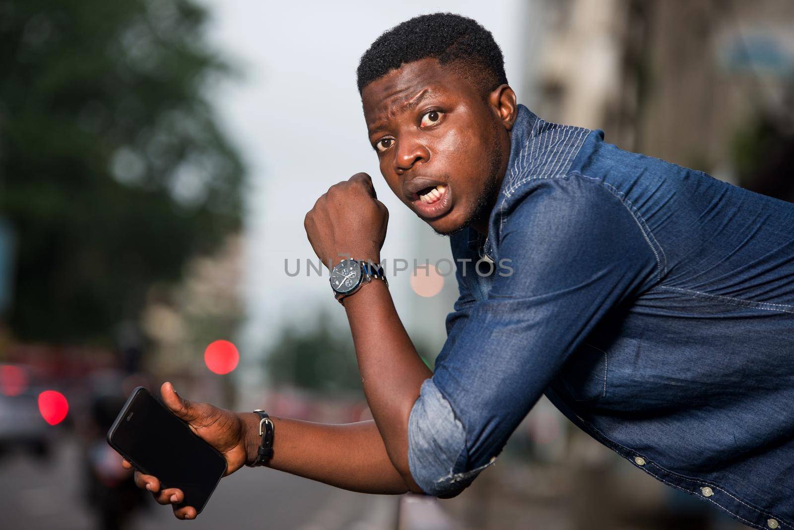 young man in jeans with his elbows on iron bar staring at the camera with surprise.