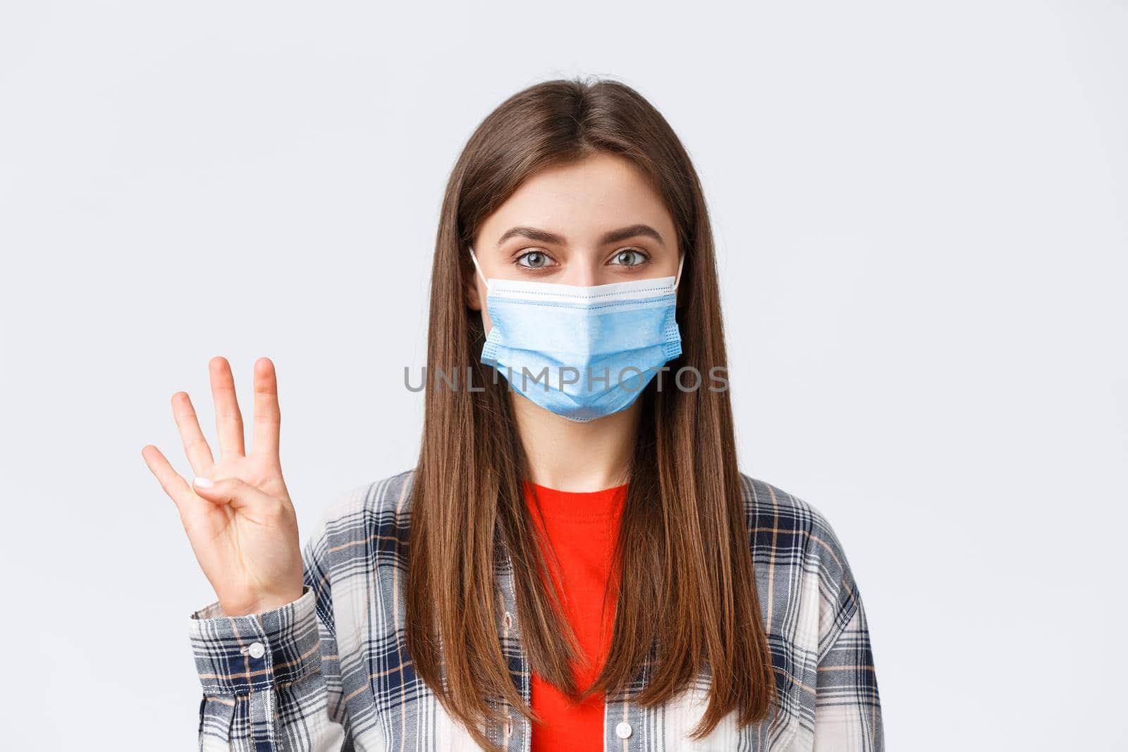 Coronavirus outbreak, leisure on quarantine, social distancing and emotions concept. Cheerful attractive woman in medical mask showing number four, make order, white background.