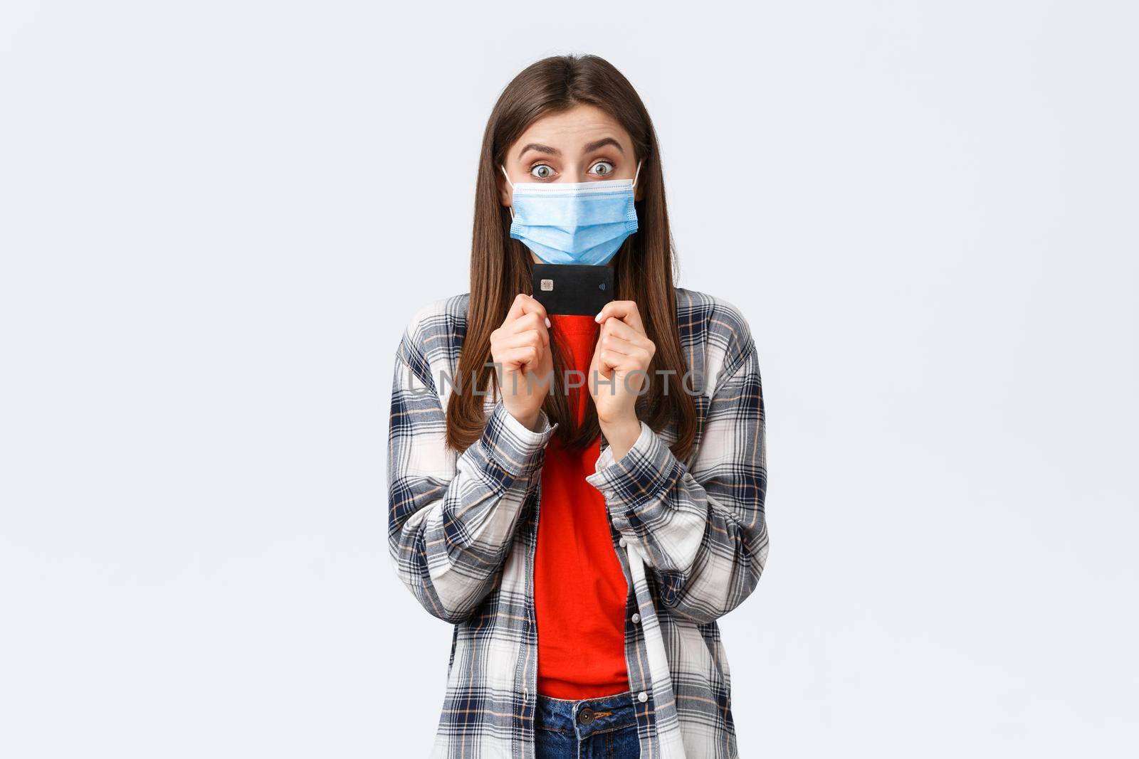 Coronavirus outbreak, working from home, online shopping and contactless payment concept. Rejoicing, happy pretty woman in medical mask showing credit card, smiling white background.