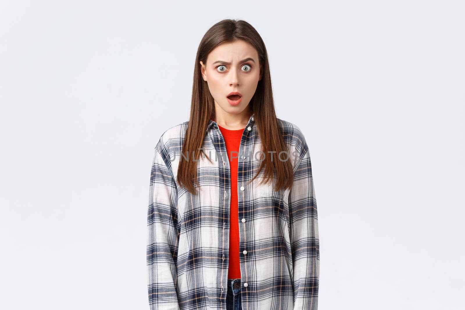 Lifestyle, different emotions, leisure activities concept. Shocked and puzzled attractive female student hear something strange, surprising news, drop jaw and staring astonished camera.