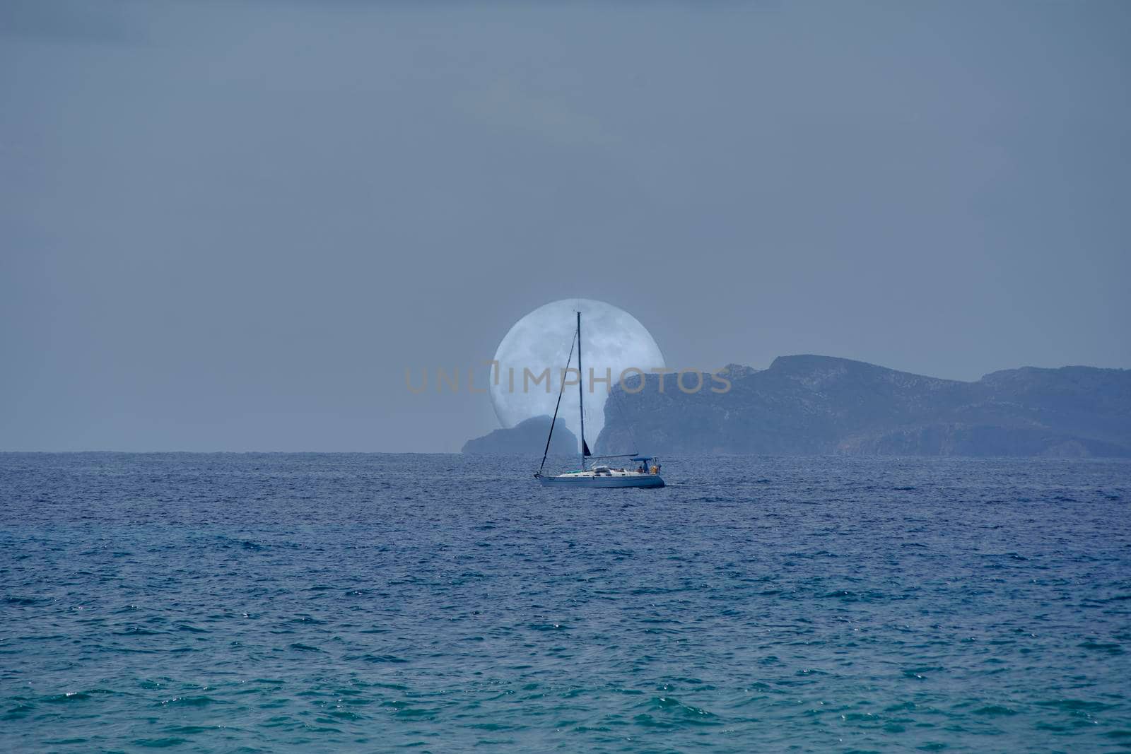 Full moon rising behind island and sailboat by raul_ruiz