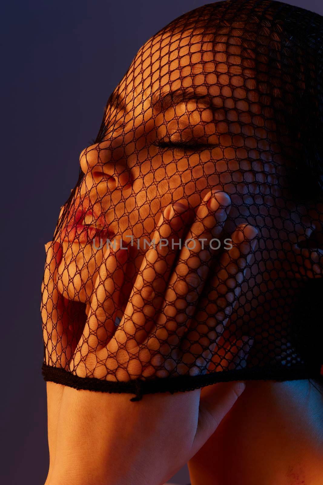 photo pretty woman black veil on the face close-up red light color background. High quality photo