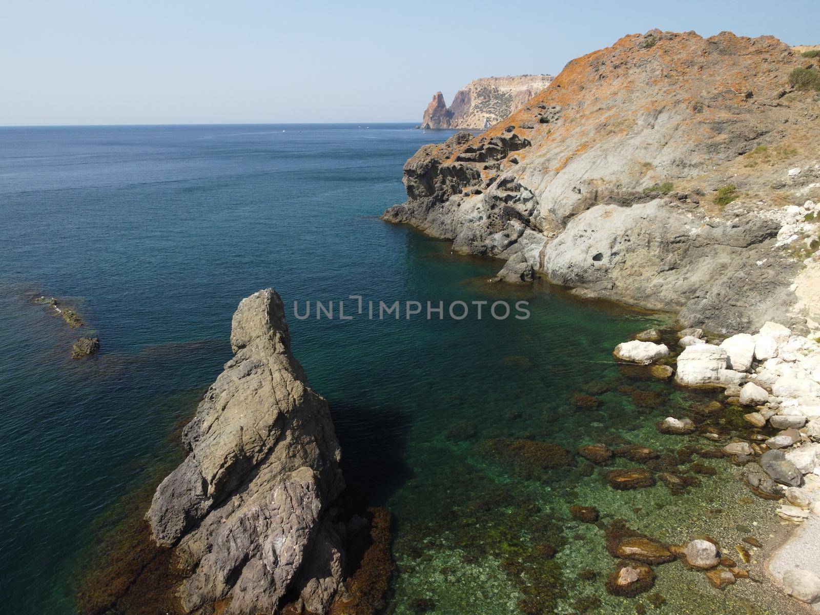 Aerial view from above on calm azure sea and volcanic rocky shores. Small waves on water surface in motion blur. Nature summer ocean sea beach background. Nobody. Holiday, vacation and travel concept by panophotograph