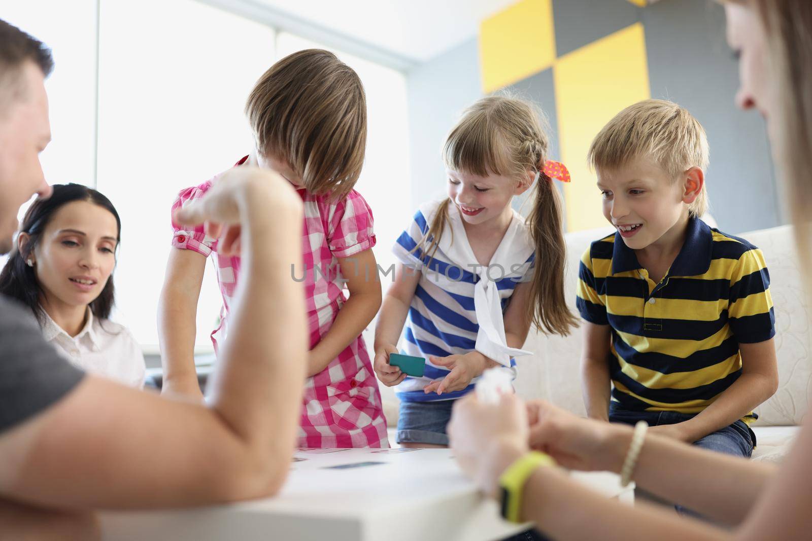 Portrait of children playing fun card game with adults, brothers and sisters having fun at home with parents. Holiday, entertainment, development concept