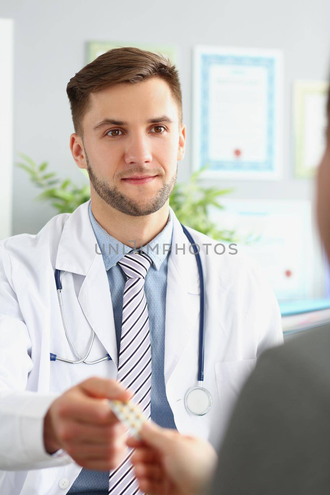 Portrait of male doctor in uniform give tablets in blister to patient. Specialist advice medication for treatment. Medicine, pharmacy, cure, help concept