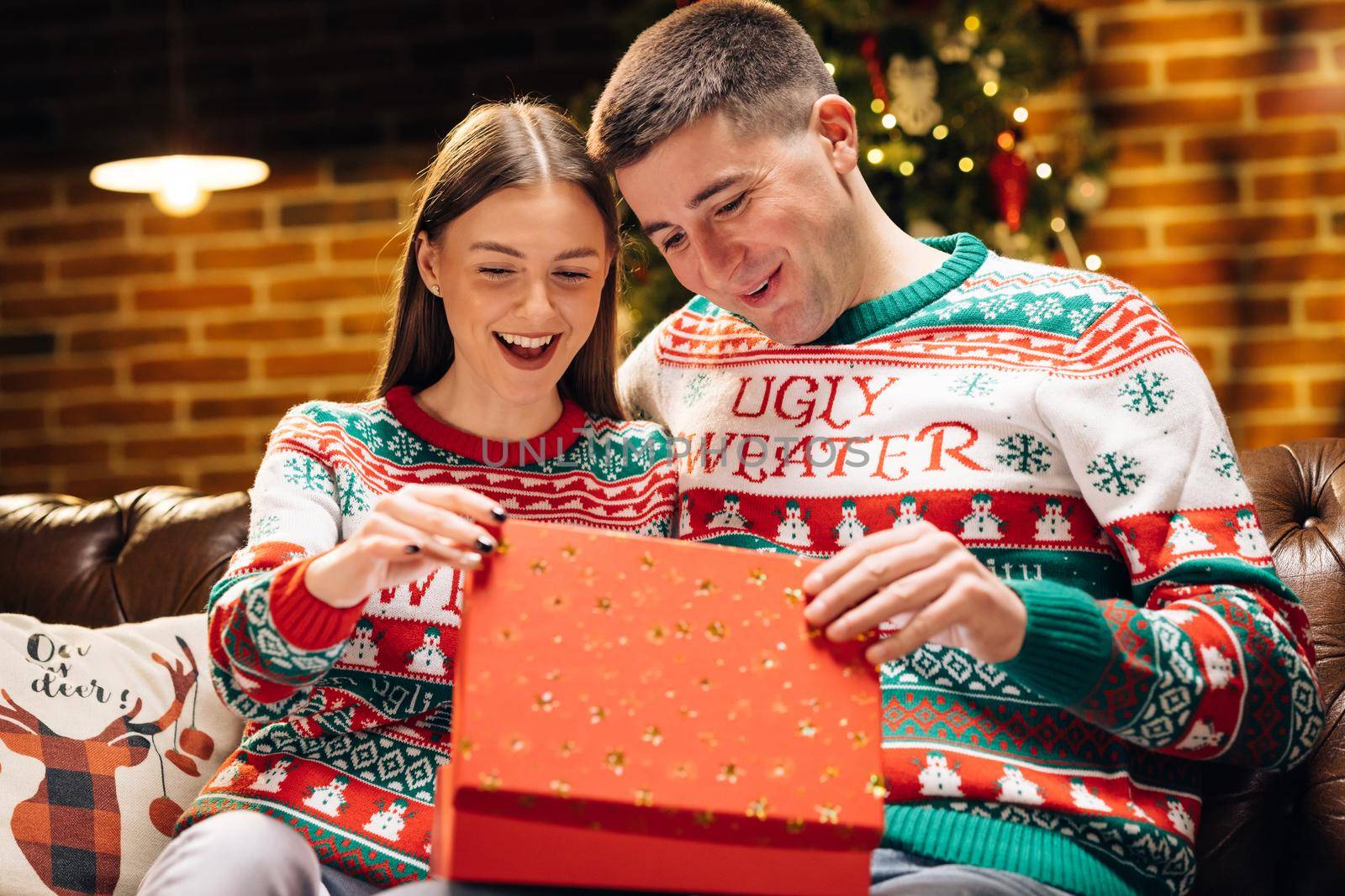 Concept of holidays, romance, surprise, e-commerce, Xmas, Holiday miracle. Happy man is making christmas gift to his beloved woman. The woman is surprised and excited after opening received gift box by uflypro