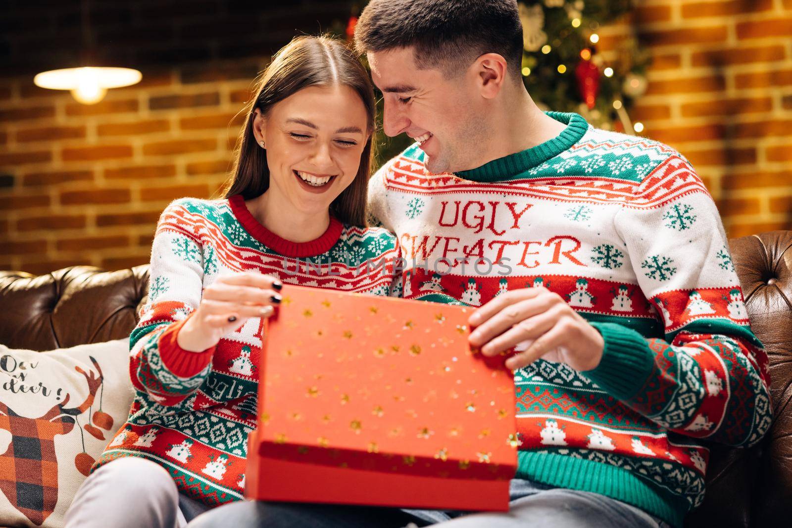 The woman is surprised and excited after opening received gift box. Concept of holidays, romance, surprise, e-commerce, Xmas, Holiday miracle. Happy man is making christmas gift to his beloved woman.