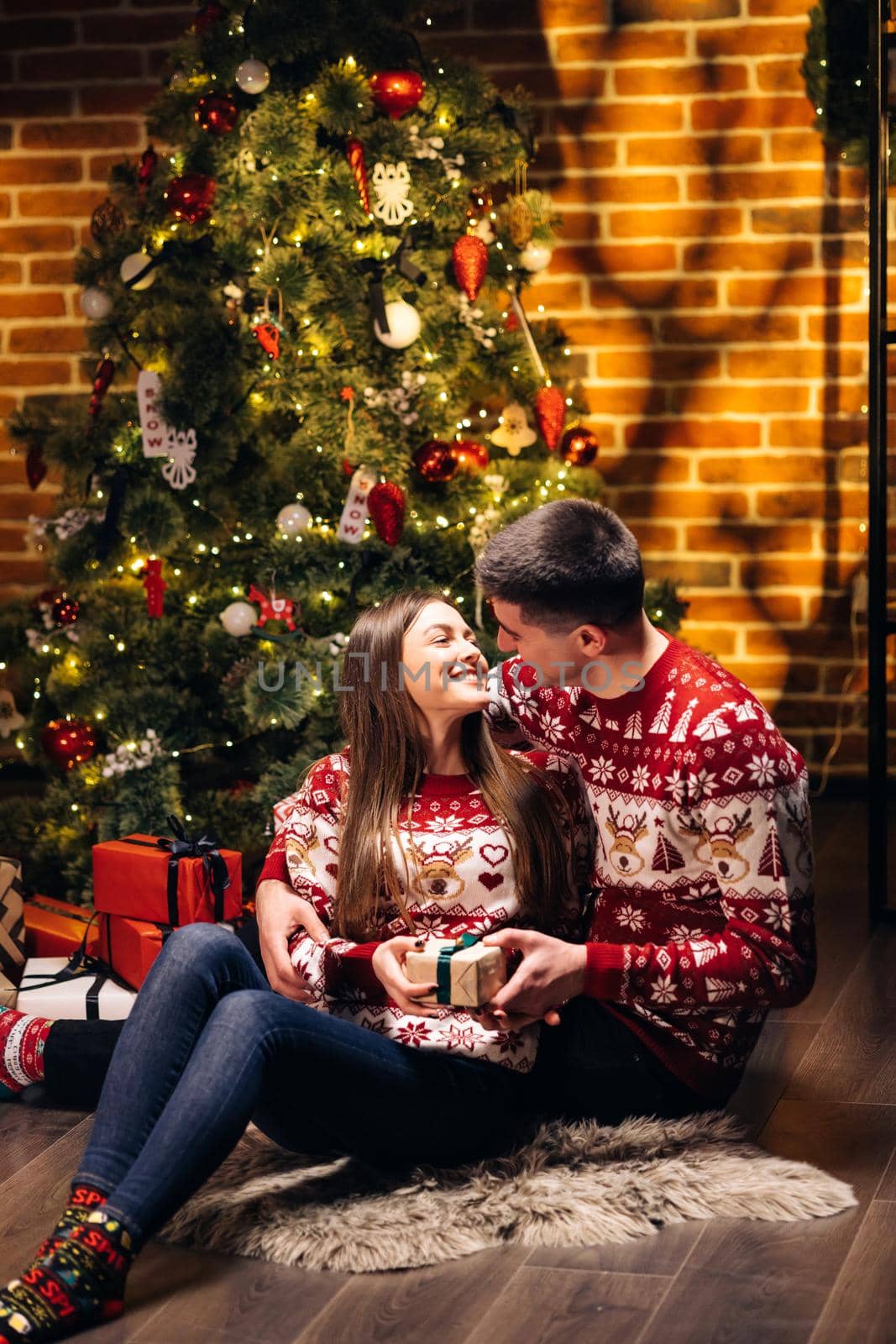 Young boyfriend making holiday surprise to his woman celebrating together giving birthday christmas present gift box. Shopping online gifts for Christmas. Love couple. Romantic date.