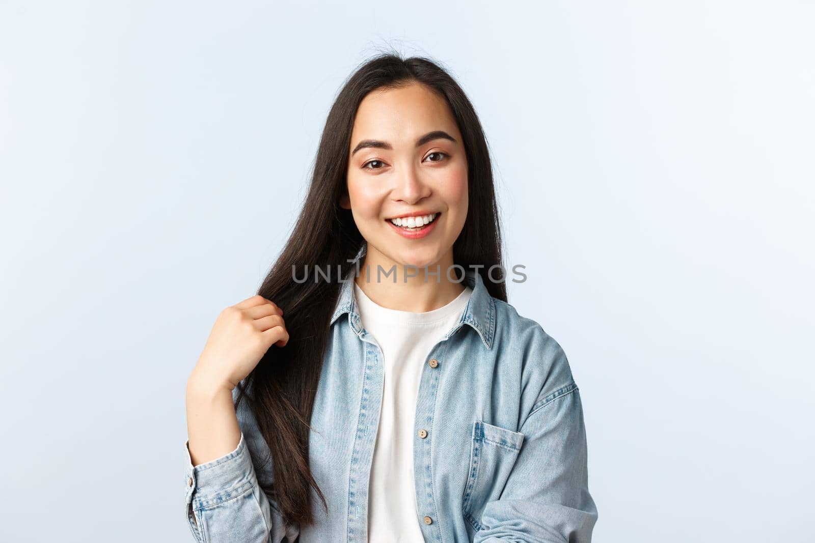 Lifestyle, people emotions and beauty concept. Carefree young asian woman talking and smiling, touching hair, recommend haircare products or beauty salon, white background.