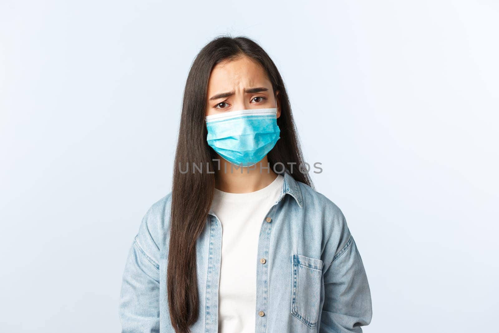 Social distancing lifestyle, covid-19 pandemic everyday life and leisure concept. Upset gloomy asian girl in medical mask looking concerned, showing empathy, frowning, got positive test coronavirus by Benzoix