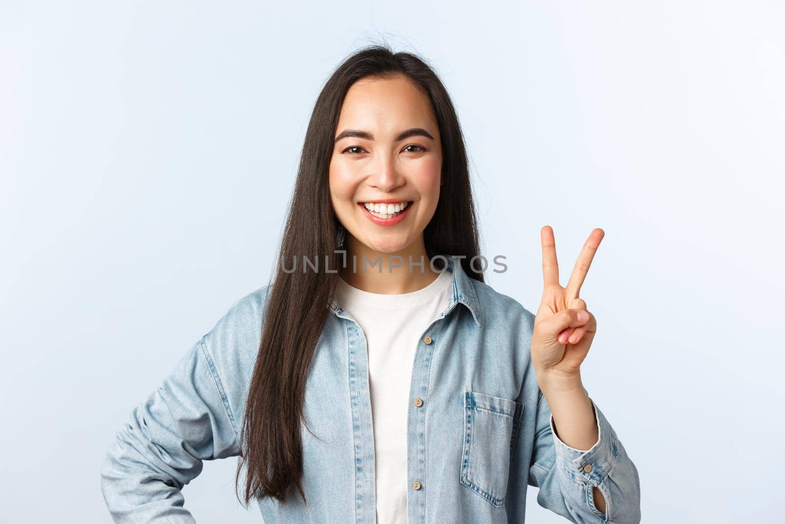 Lifestyle, people emotions and beauty concept. Cheerful cute asian girl, female student in college looking happy, show peace sign and smiling broadly, standing white background by Benzoix