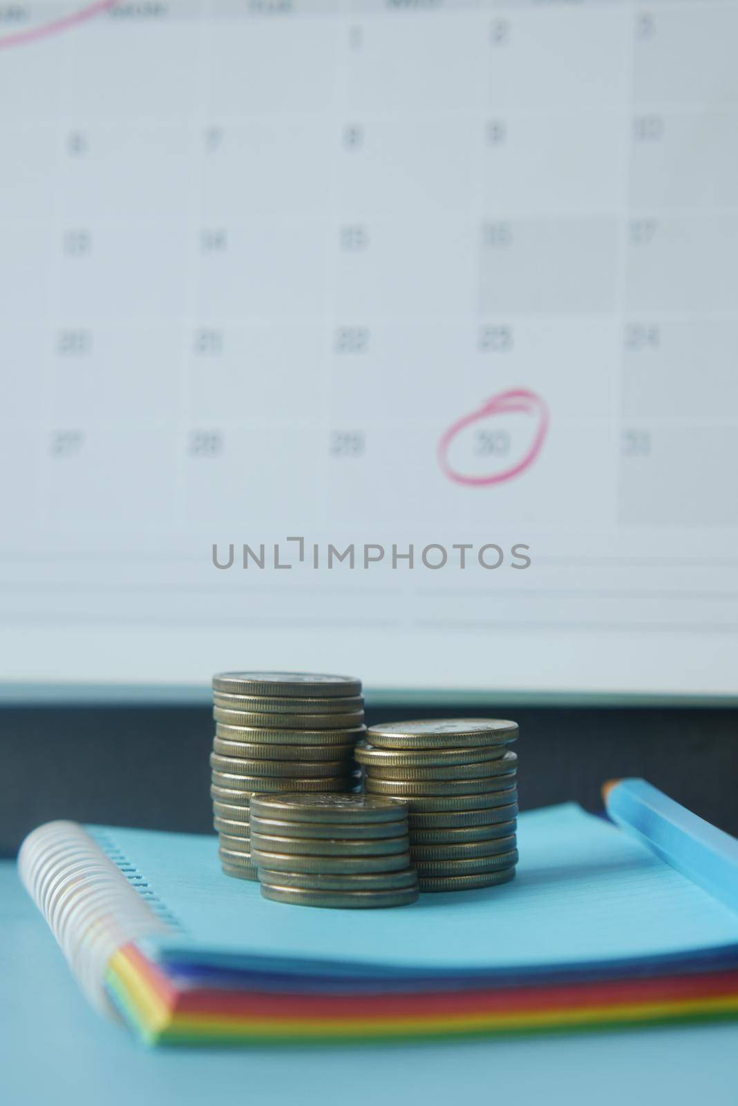 stack of coins and calendar on white background .