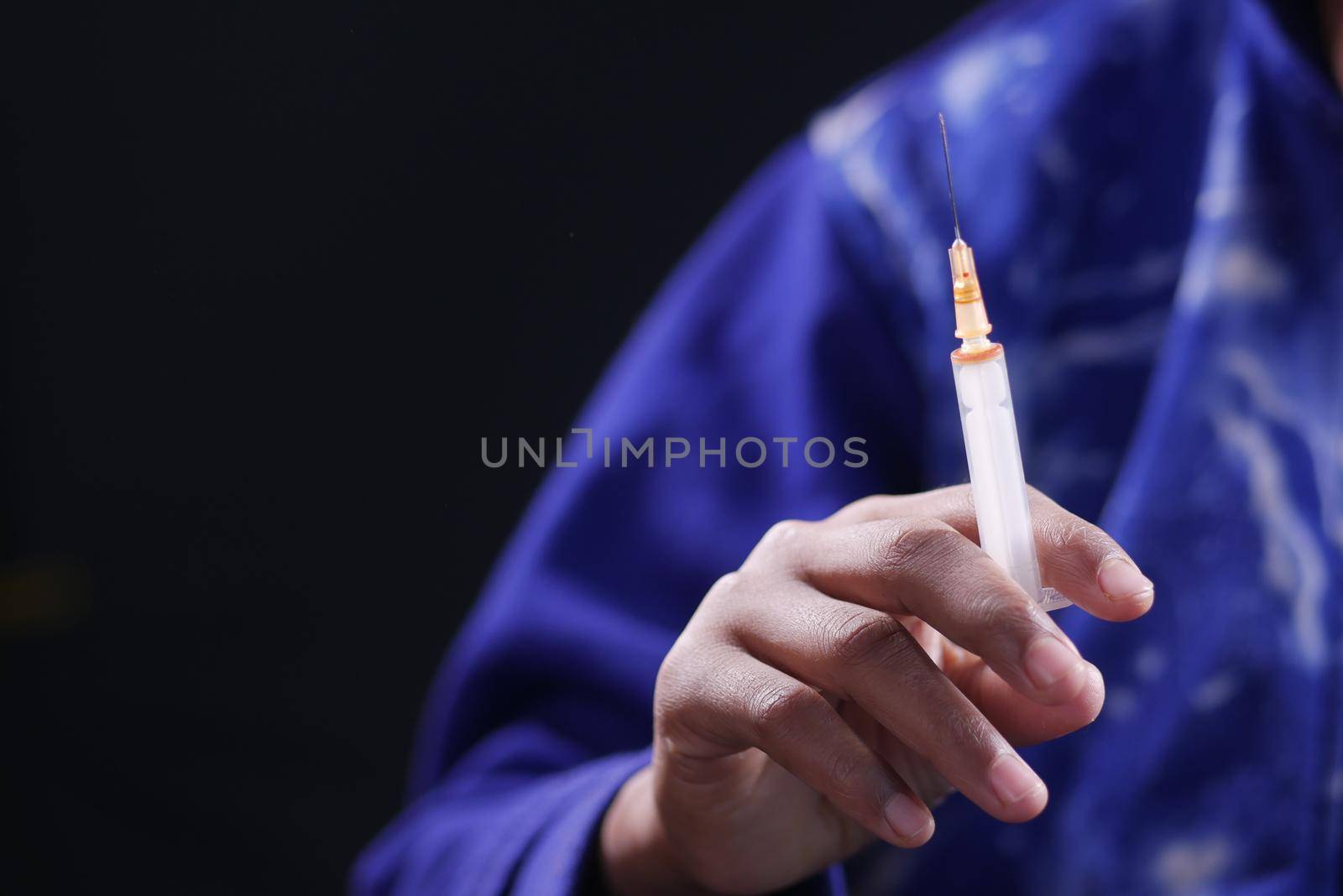 drug addiction concept with hand holding pills and syringe laying on floor .