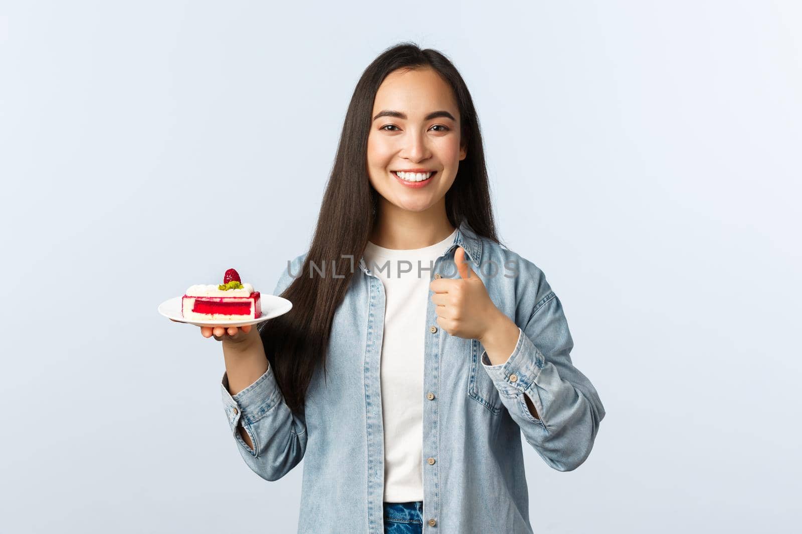 Social distancing lifestyle, covid-19 pandemic, celebrating holidays during coronavirus concept. Happy cheerful asian female show thumbs-up and smiling, holding delicious cake dessert.
