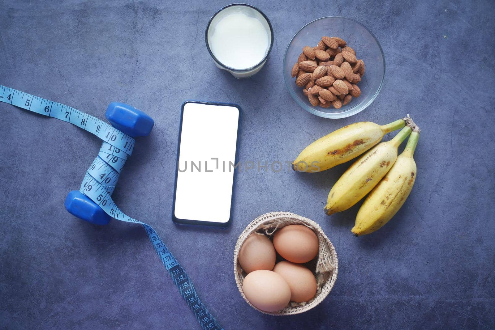 smart phone with empty screen , eggs , milk and almond nut in table .