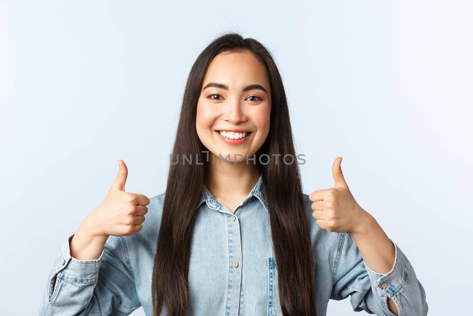 Lifestyle, people emotions and beauty concept. Cheerful friendly-looking asian girl smiling happy, show thumbs-up in approval, agree and support friend choice, white background.