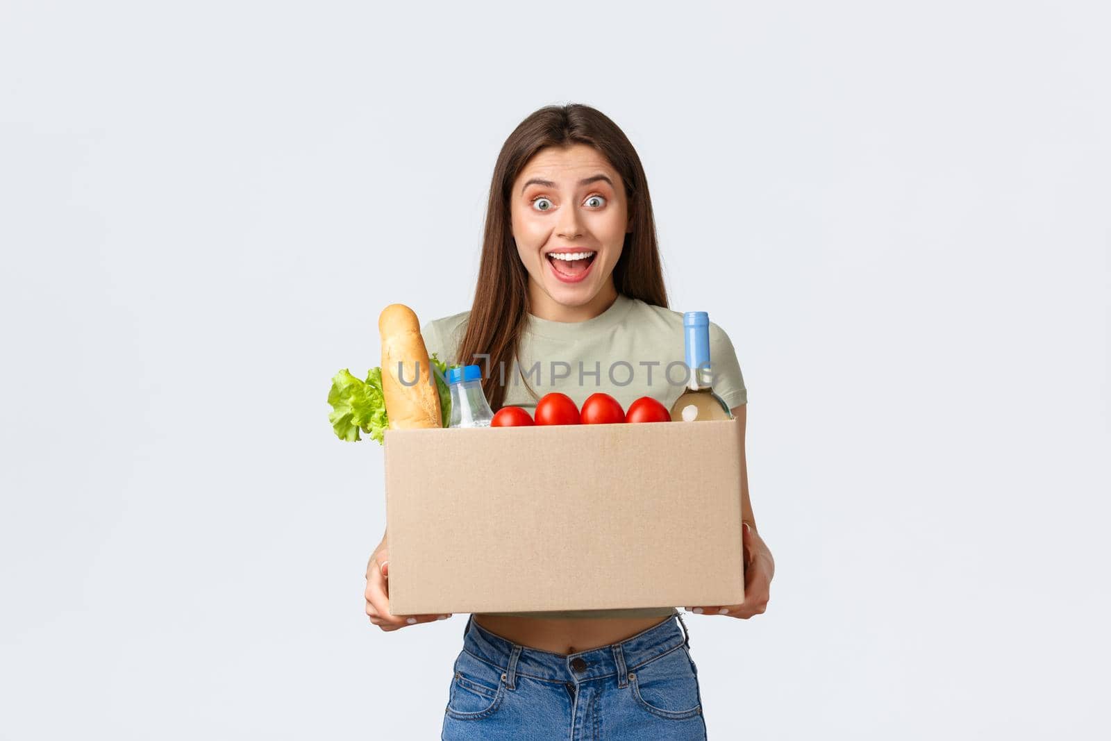 Online home delivery, internet orders and grocery shopping concept. Excited woman satisfied with quality of deliver service from local shop, holding groceries in box and smiling amazed.