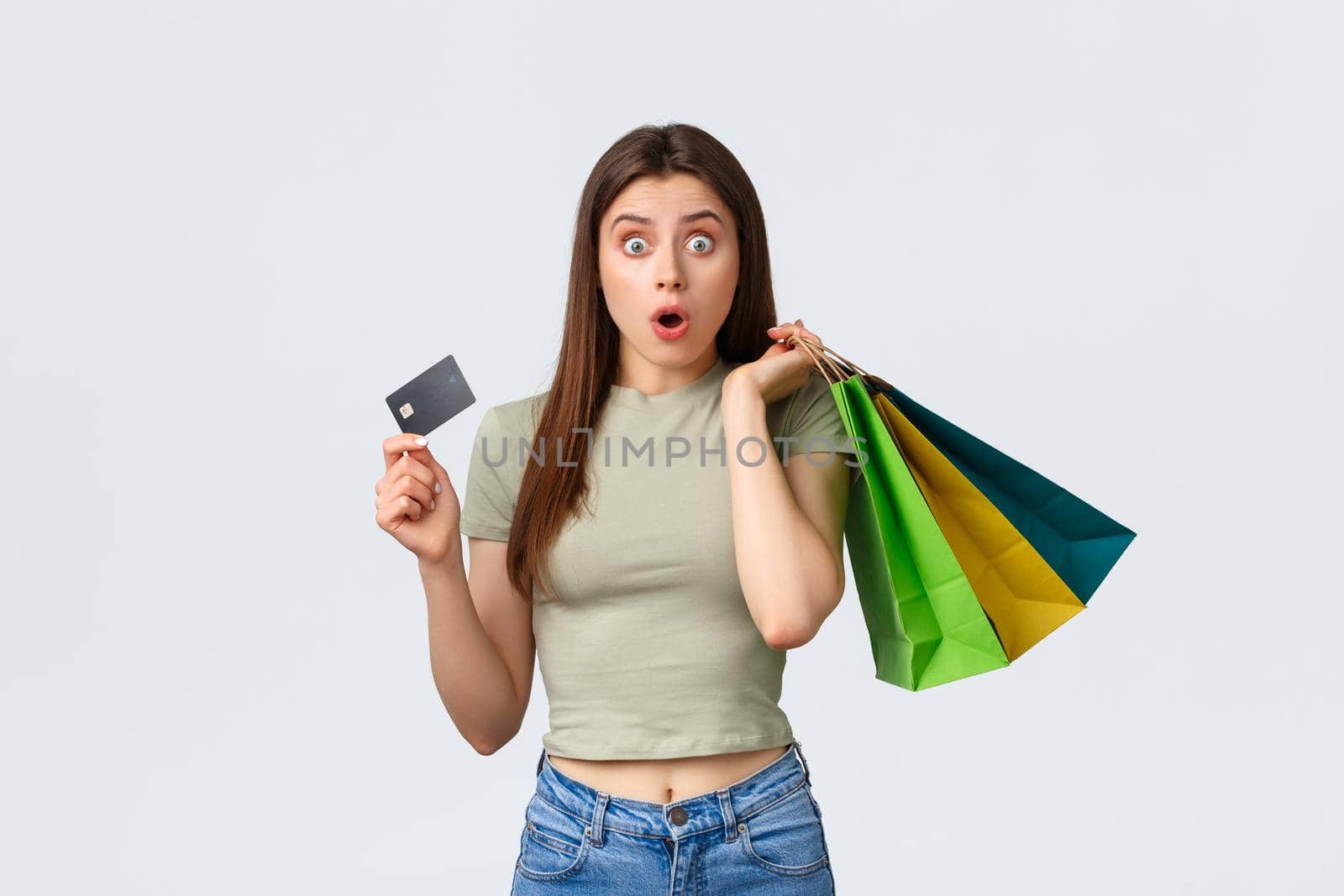 Shopping mall, lifestyle and fashion concept. Shocked and impressed woman with credit card buying new clothes, seeing special discount, hurry up to cashier with bags.