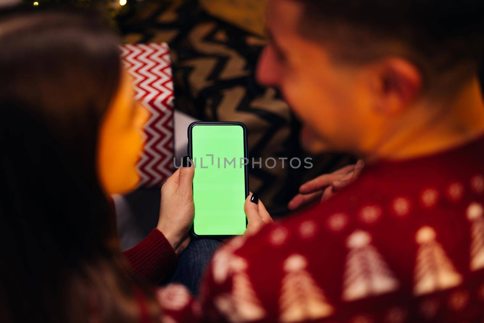 Caucasian couple using smartphone for christmas video call with green mock up screen. Christmas, festivity and communication technology by uflypro